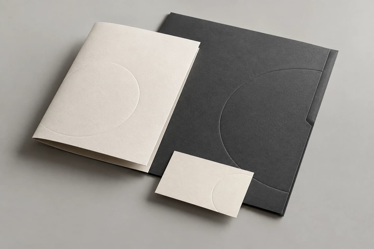 Minimal cream stationery and a charcoal folder with subtle circular embossing.