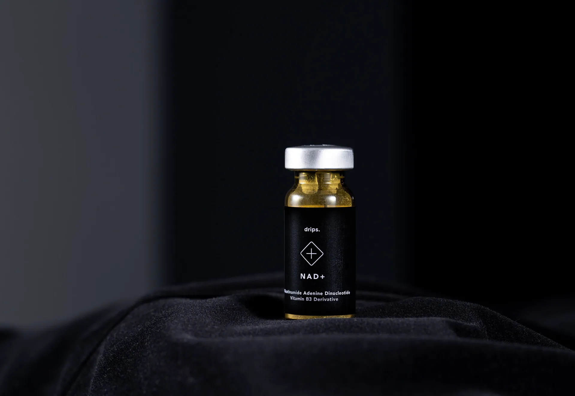 A Drips NAD+ vial on black cloth.
