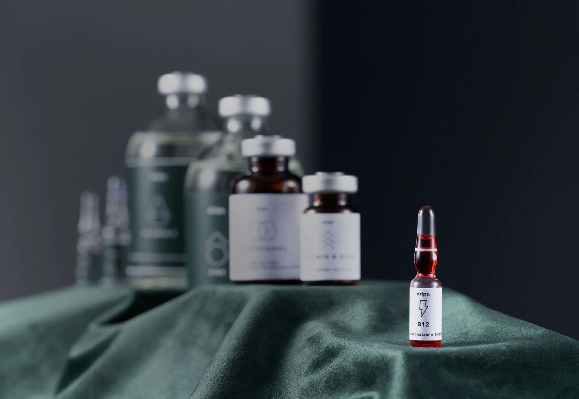 A Drips B12 ampoule in front of bottles on green cloth.