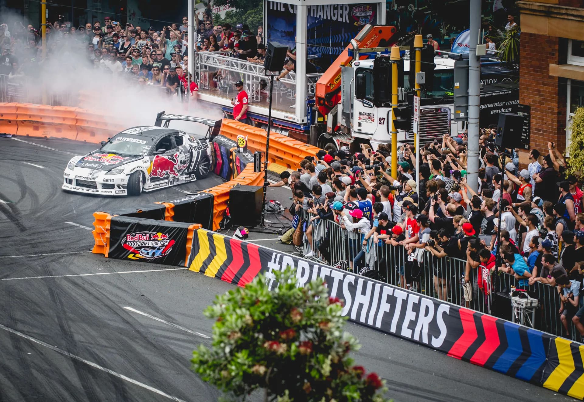 A drift car sliding past the crowd on Quay Street in tyre smoke, behind #DRIFTSHIFTERS barriers.