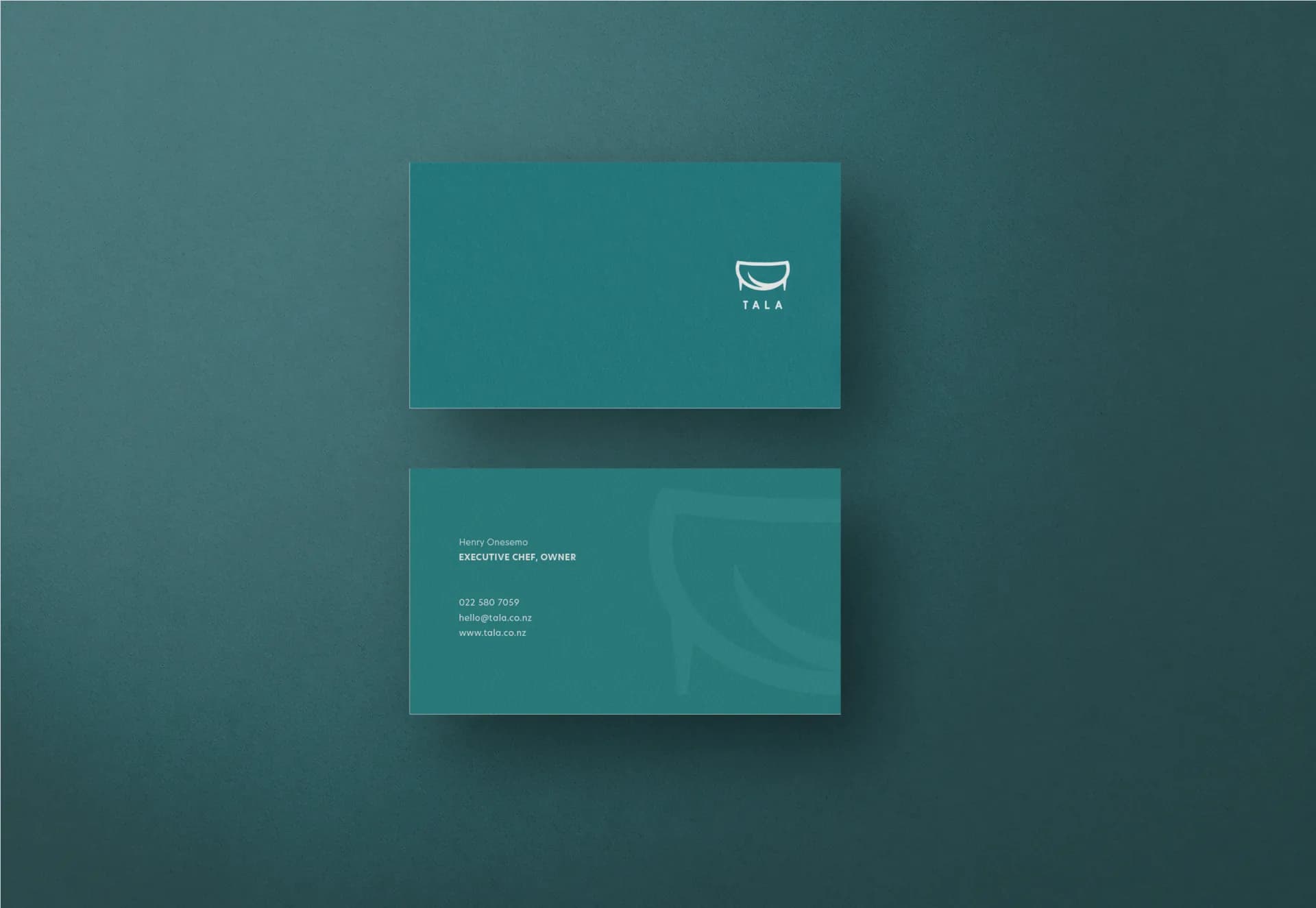 The front and back of a teal Tala business card.