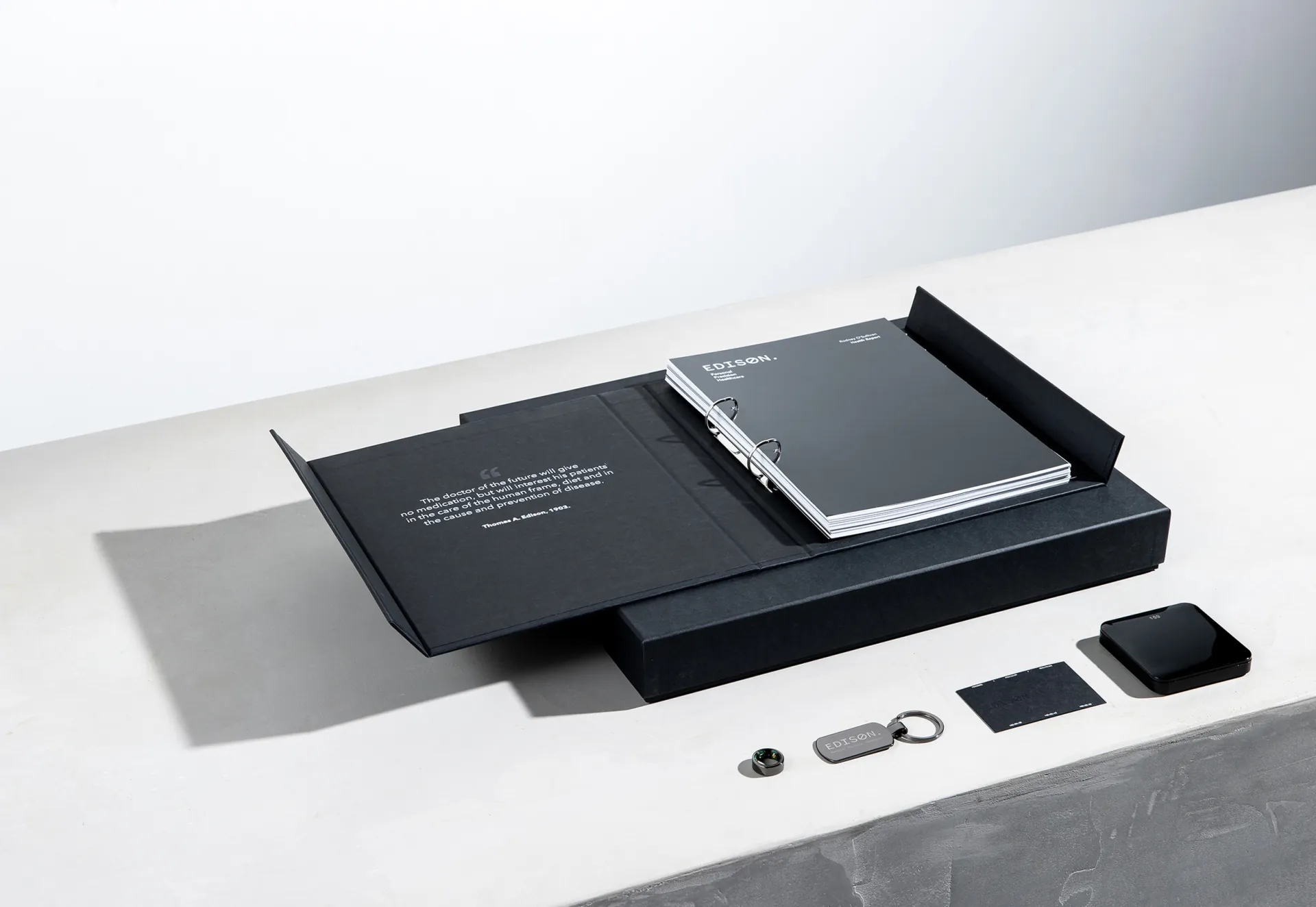The kit open in its folder, the protocol booklet inside and the keyring, card and power bank laid out in front.