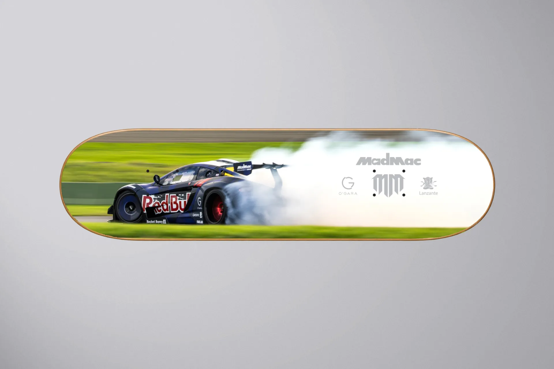 A MadMac skateboard deck printed with the car drifting in smoke.
