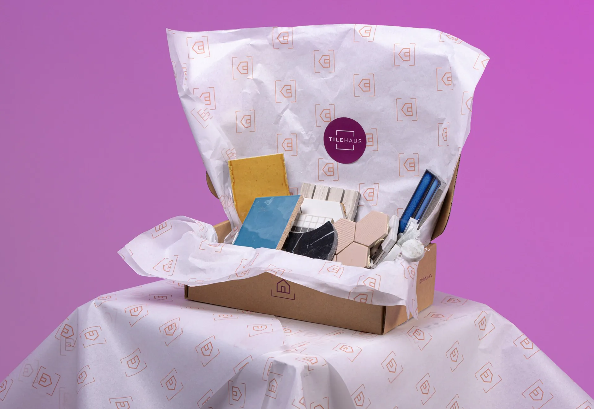 An open TileHaus box of tile samples wrapped in printed tissue paper.