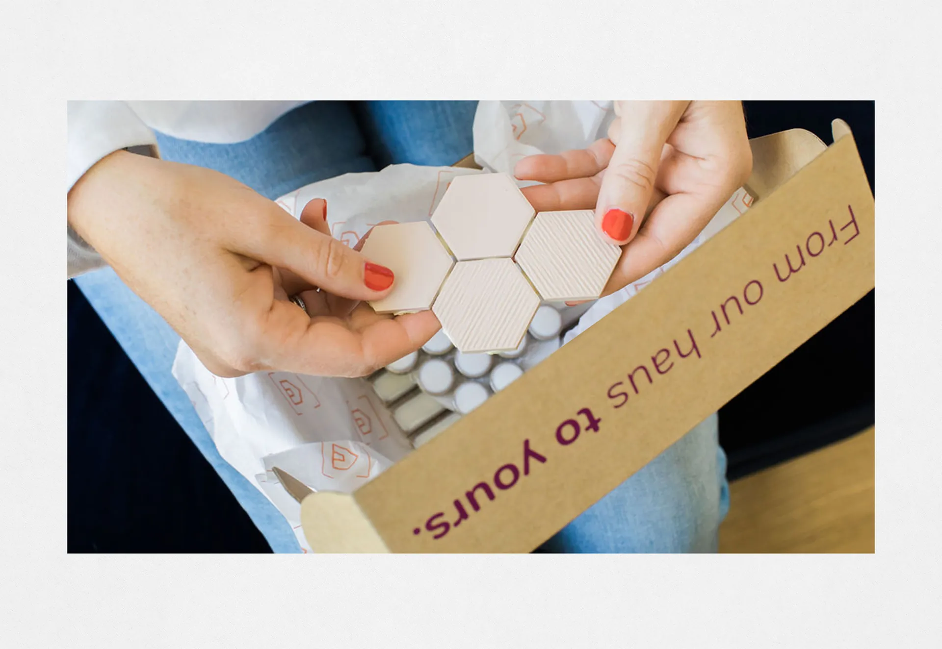 Hands lifting hexagonal tile samples out of a TileHaus box printed “From our haus to yours.”