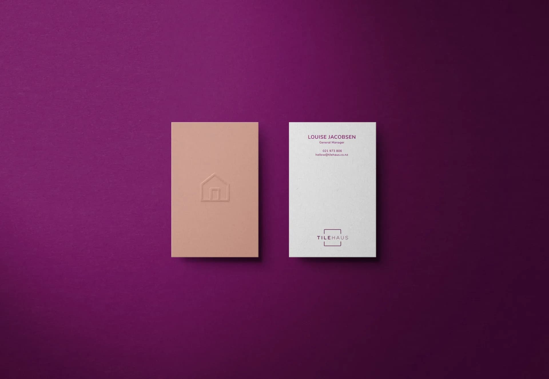 A pink and a white TileHaus business card on deep plum.